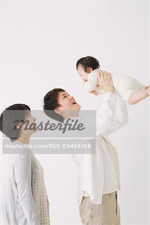 Young adult couple and son. Father lifting his son and smiling