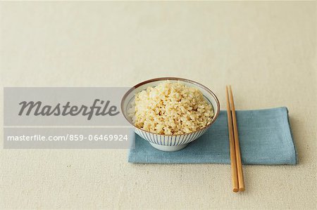 Cup of brown rice and chopsticks on a table