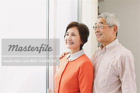 Senior adult couple cuddling while looking outside the window