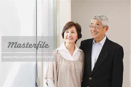 Senior adult couple cuddling while looking outside the window