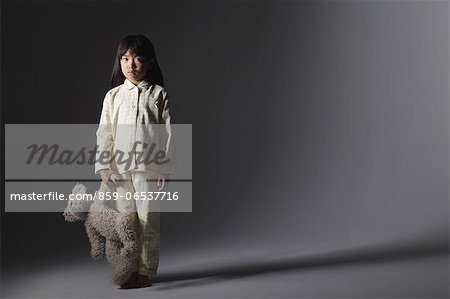 Girl in a pajama holding a teddy bear