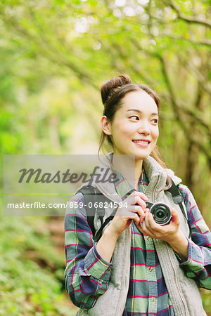 Young girl with camera in a forest smiling away