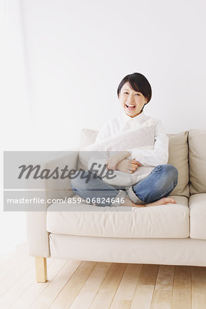 Young woman in a white shirt sitting on sofa