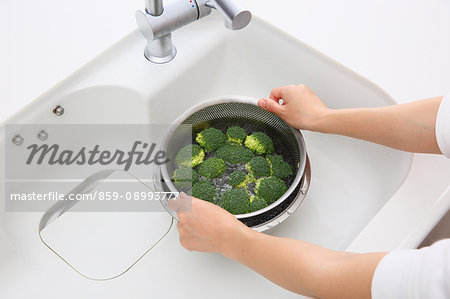 Japanese woman washing broccoli in the kitchen