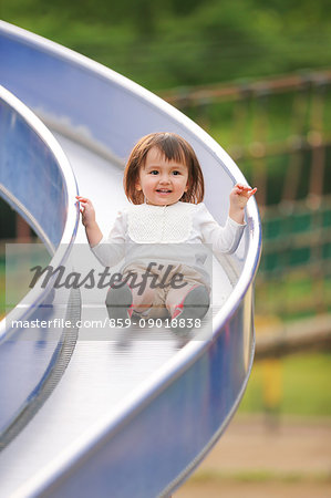 Mixed-race young girl playing on slide at the park
