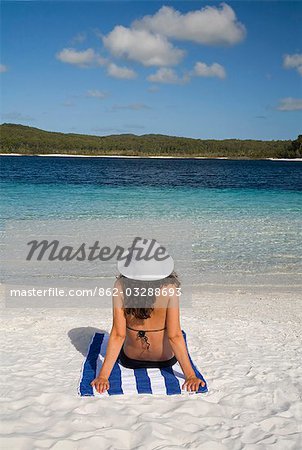 A woman looks out over the clear waters and white sand beach of Lake McKenzie on Fraser Island.