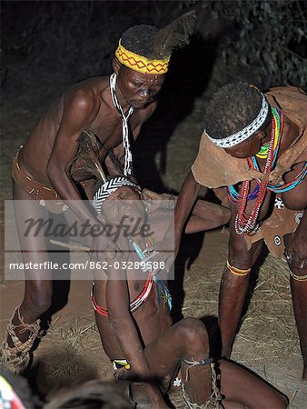 A bushman,or San,collapses in a trance and is helped by members of his band during a sing-song round their campfire. These NS hunter gatherers live in the Xai Xai Hills close to the Namibian border. Their traditional way of life is fast disappearing.