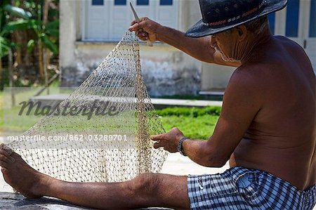 Old fisherman repairs his fishing net on a Sunday morning on the Tinhare archipelago,Bahia,north eastern Brazil