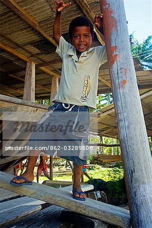 Brazil,Bahia,Bahia de Camamu. Small boy playing within the boat building yards on the island.