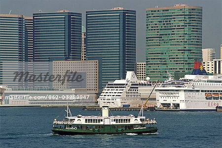 One of Hong Kong's iconic Star Ferries crosses the harbour with the Ocean Terminal and highrises of Tsim Sha Tsui in Kowloon in the background.