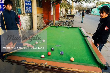 China,Beijing. Boys playing pool outside on the street of a local neighbourhood Hutong.