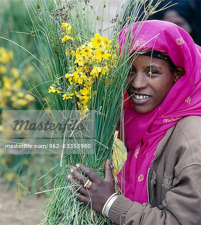 A woman sells yellow daisies by the side of the road in the outskirts of Addis Abeda,Ethiopia's capital city.These daisies (Bidens sp.) are known by Ethiopians as Meskal daisies because they flower in September at the time of the Orthodox Christian Festival of Meskal,or the Finding of the True Cross celebration.