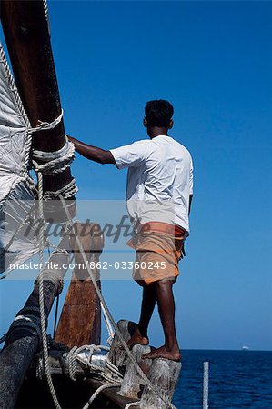 One of the crew members of S/Y Sanjeeda standing on the rail of the boat. Sanjeeda is a traditional kotiya dhow of the type that traded throughout the Indian Ocean