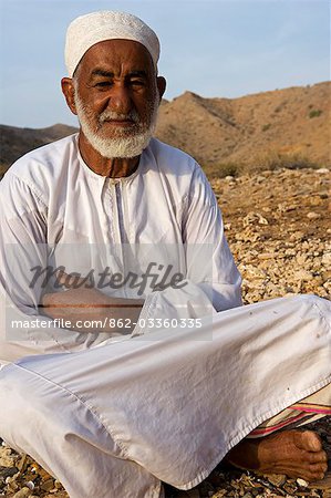 Oman,Muscat Region,Bandar Khayran. A old farmer sits down for a chat dressed in traditional Omani clothing.