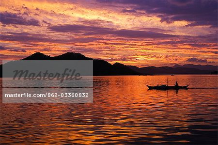 Philippines,Palawan Province,Busuanga Island,Coron Town. Sunset over Coron Bay and fishing boat.