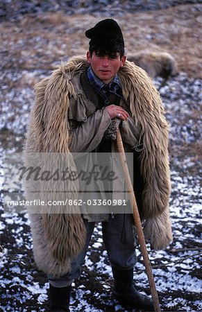 Local shepherd with traditional sheep skin coat and dog