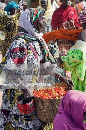 Mali,Djenne. A woman carries a basket of red chillies at Djenne market. The weekly Monday market is thronged by thousands of people and is one of the most colourful in West Africa.