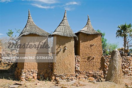 Mali,Dogon Country,Koundu. A small settlement built among rocks near the Dogon village of Koundu. Dwellings have flat roofs while granaries to store millet have pitched thatched roofs. The Dogon are animists. The sacred earthen mound on the right with an ostrich egg on top is an altar used for sacrifices by the village hogon or priest to appease the ancestors and purify the village.