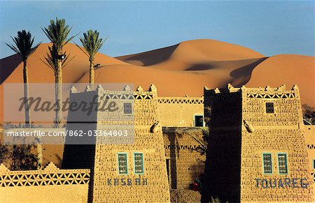 A desert kasbah backing onto the giant sand dunes of Erg Chebbi in eastern Morocco.