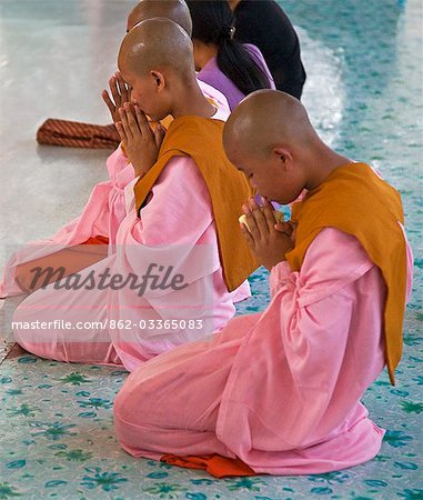 Myanmar,Burma,Yangon. Young Buddhist nuns pray at the site of the reclining Buddha in Yangon.