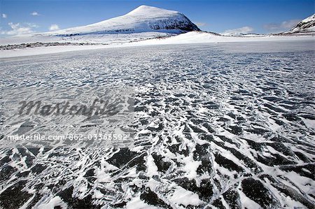 Norway,Troms,Lyngen Alps. High on the plateau the pressure of freezing and weather conditions creates dramatic patterns and conditions on the flat,canvas like,surfaces of the areas lakes.