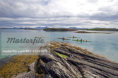 Norway,Nordland,Helgeland. Exploring Norway's coastal archipelago,a team of sea kayakers make thier way thorugh a string of islands.