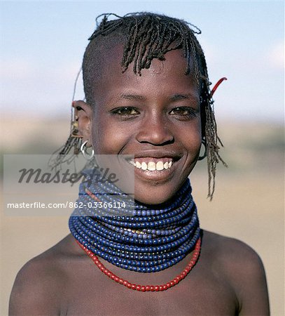 A pretty young Turkana girl has already had the flesh below her lower lip pierced in readiness for a brass ornament after her marriage. The rims of her ears have also been pierced and the holes kept open with small wooden sticks.