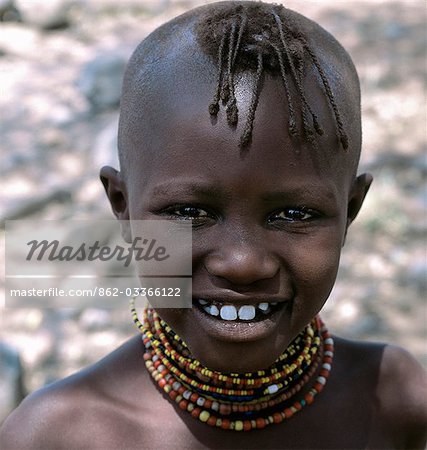 A young Turkana girl with her head shaved except for a tuft,which is braided. This is the usual hairstyle for women and girls.