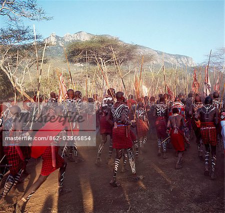 Africa,Kenya,Kajiado District,Ol doinyo Orok. A large gathering of Maasai warriors dance with raised sticks after they return from daubing themselves with white clay during an Eunoto ceremony when the warriors become junior elders and thenceforth are permitted to marry