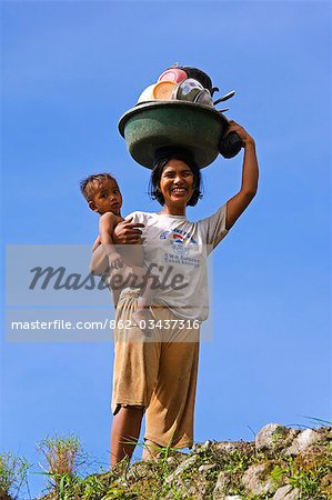 Philippines,Luzon Island,The Cordillera Mountains,Kalinga Province,Tinglayan. Mother and baby carrying dishes in Dananao village.