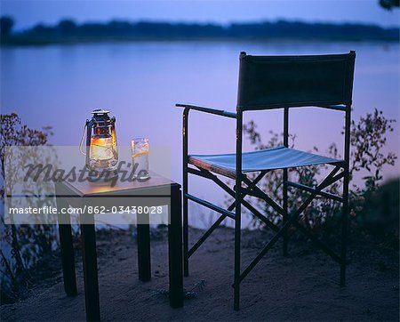 Zambia,Lower Zambezi National Park,Old Mondoro Bushcamp. Gin and tonic by the light of a hurricane lamp; looking out over the Zambezi River.