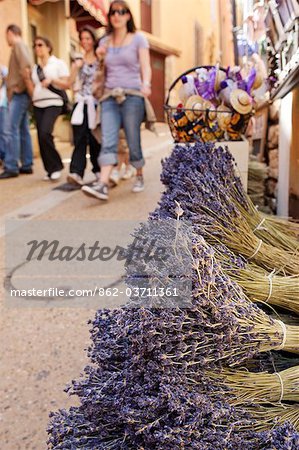 Rousillion; France. People walking down a street with lavender for sale in the foreground