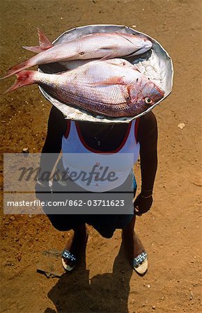 Ghana,Volta Region,Agomanya. Girl selling fish at the market from a balanced plate on her head.