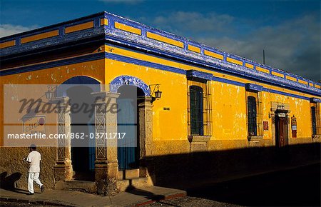 A man walks along the a street in downtown Antigua beside the brightly painted houses.