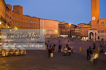 Italy,Tuscany,Siena. Tourists visit the Piazza del Campo,Siena's central medieval square whose focal point is the Palazzo Publico or Townhall with its 102m high bell tower,the Torre del Mangia.