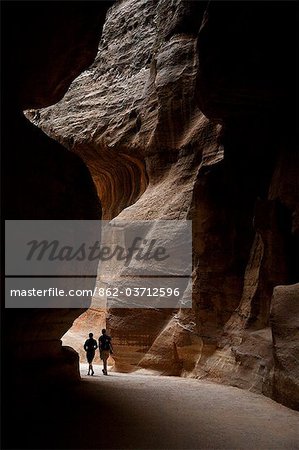 Jordan, Petra. A couple wanders down the depths of the Siq at Petra.