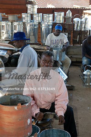 Malawi, Zomba. In the covered market, a group of blacksmiths work as a team to produce domestic holdhold goods Malawi, Zomba. In the covered market, a group of blacksmiths work as a team to produce domestic holdhold goods