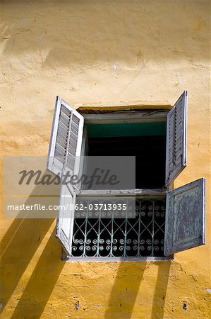 Tanzania, Zanzibar, Stone Town. A shuttered window in a brightly-painted wall of an old building in Stone Town.