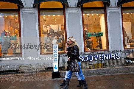 Russia, St. Petersburg; Two Russian girls walking along Nevski Prospekt in front of shops