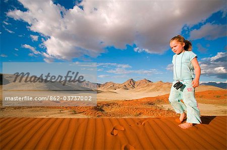 Namib Rand Nature Reserve, Namibia. A young boy runs across the rippled surface of a sand dune in the Namib Desert.