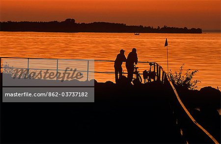 Sweden, Ostergotland, Vadstena, Lake Vattern. Cyclists pause near Vadstena's marina on the shores of Lake Vattern.