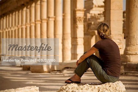 Syria, Palmyra. A tourist sits amongst the ancient ruins of Queen Zenobia's city at Palmyra.