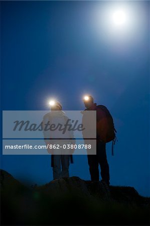 Gilar Farm, Snowdonia, North Wales.  Man and woman trekking at night by headtorch and moonlight.