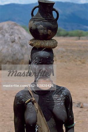 A woman of the Mursi tribe. Once married Mursi women pierce their lower lip and stretch it by inserting  increasingly large plugs until they can wear a clay lip plate. The size of the lip plate reflects the bride price paid by their husband. Within the Omo Valley, the Mursi have a reputation for being extremely fierce and aggressive but also for their skill at making pots. This women carries a pot