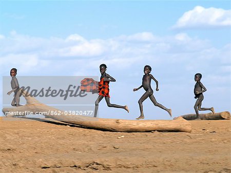 Young Dassanech boys run along a bank of the Omo River in Southwest Ethiopia.The Dassanech speak a language of Eastern Cushitic origin.They live in the Omo Delta and they practice animal husbandry and fishing as well as agriculture.