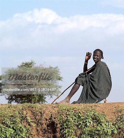 A Dassanech youth sits on his wooden stool on a bank of the Omo River.Every man has his own stool, which doubles as a pillow at night.The Omo Delta of southwest Ethiopia is one of the least accessible and least developed parts of East Africa.As such, the culture, social organization, customs and values of the people have changed less than elsewhere.