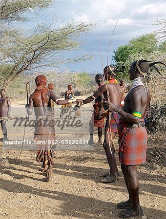 A Hamar woman implores a man to whip her at a Jumping of the Bull ceremony.Female friends and relatives of the initiate are willing whipped with pliable sticks to show their solidarity and love for him. They do not flinch or show any sign of pain.The semi nomadic Hamar of Southwest Ethiopia embrace an age grade system that includes several rites of passage for young men.