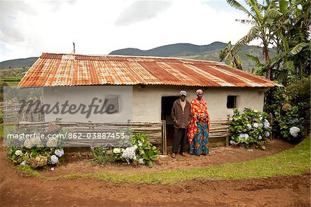 Burundi. A couple outside a traditional house on their farm.
