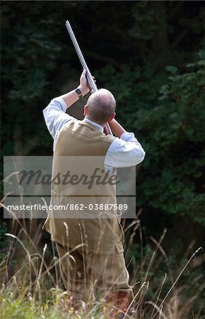 UK. Wiltshire. A man fires his shotgun at a driven partridge shoot.