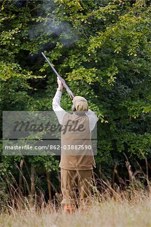 UK. Wiltshire. A man fires his shotgun at a driven partridge shoot.